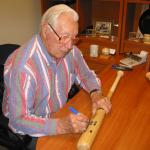 Bob Feller autographing bats at National Sports Distributors