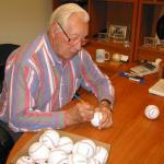Bob Feller signing baseballs for National Sports Distributors