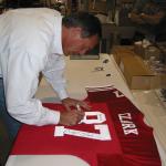 Dwight Clark autographing authentic jerseys for National Sports Distributors