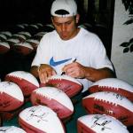 Mark Brunell autographing the white panel footballs designed by National Sports Distributors