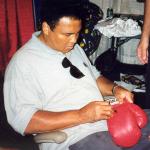 Muhammad Ali autographihng boxing gloves for National Sports Distributors