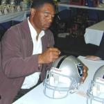 Marcus Allen autographing Raider Helmets for National Sports Distributors