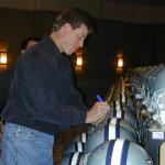 Troy Aikman autographs helmets for National Sports Distributors