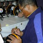 Dwight White autographing Steel Curtain helmets for National Sports Distributors