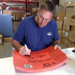 Dwight Clark signing Candlestick Park seatback at NSD warehouse