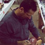 Steve Largent autographing footballs for National Sports Distributors