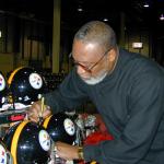 LC Greenwood autographing Steel Curtain helmets for National Sports Distributors