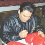 Roberto Duran autographing boxing gloves for National Sports Distributors