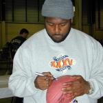 Ron Dayne autographing footballs for National Sports Distributors