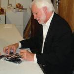 Ken Stabler autographing 8x10 photos for National Sports Distributors