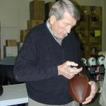 Johnny Unitas autographing Throwback Duke Footballs for National Sports Distributors